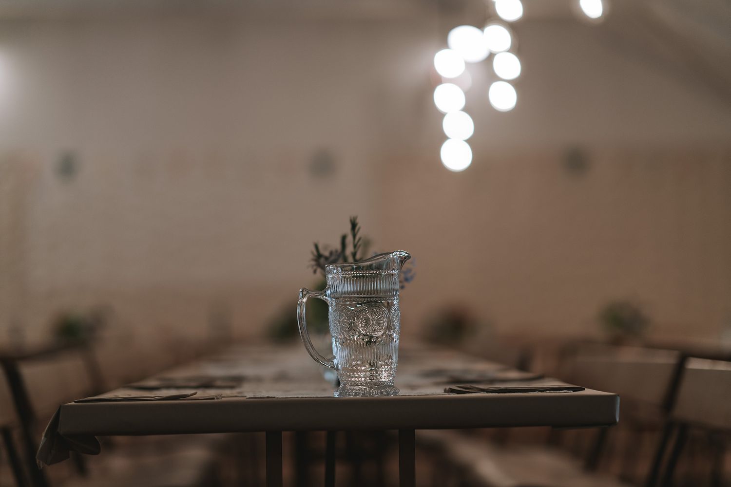 An elegant wedding reception venue with soft lighting showcases a rustic wooden table setup.