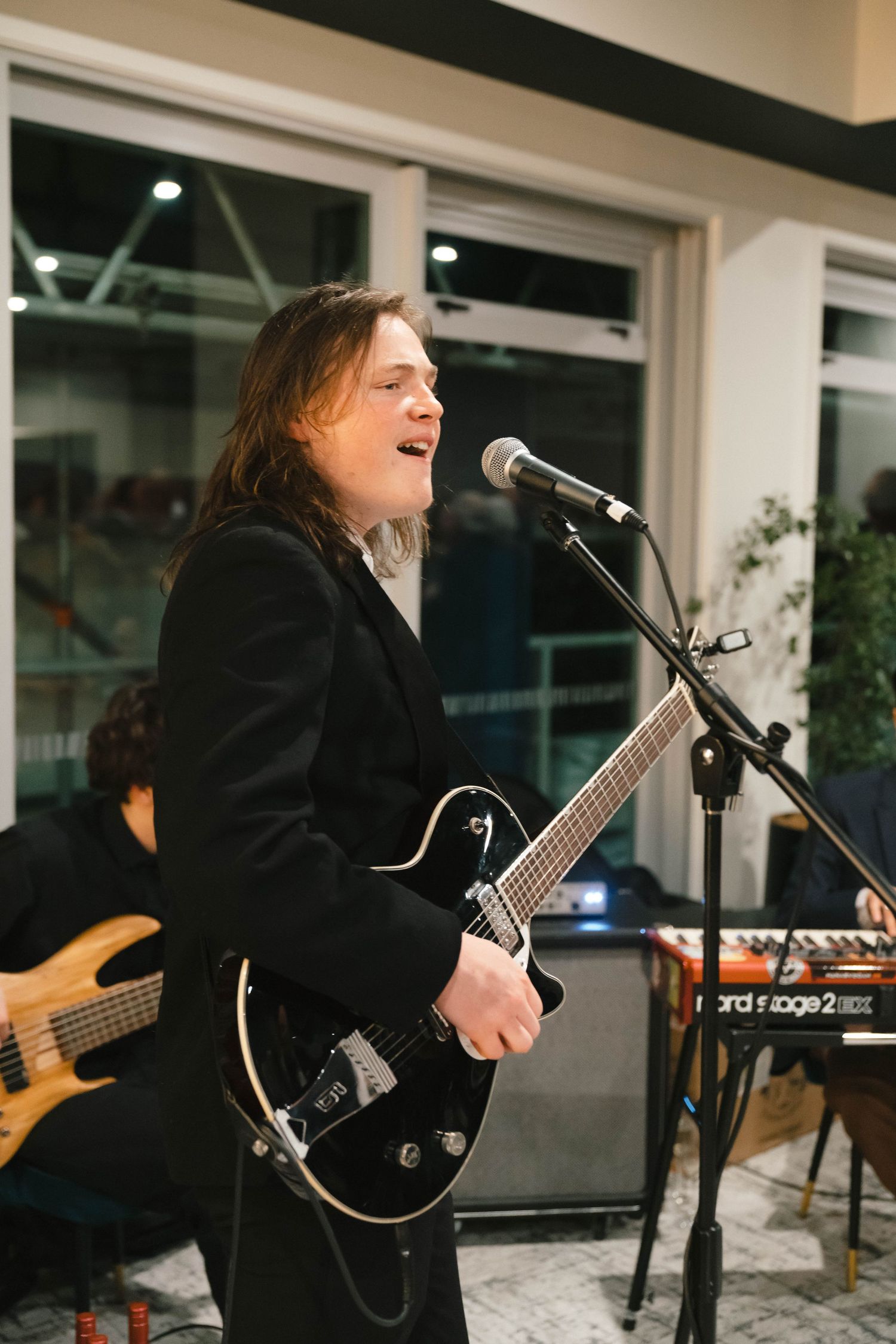 Musician performs passionately while singing and playing electric guitar at indoor venue.