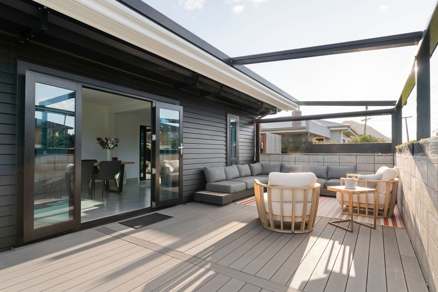 Modern rooftop terrace with wooden decking, glass railings, and outdoor furniture for relaxation.