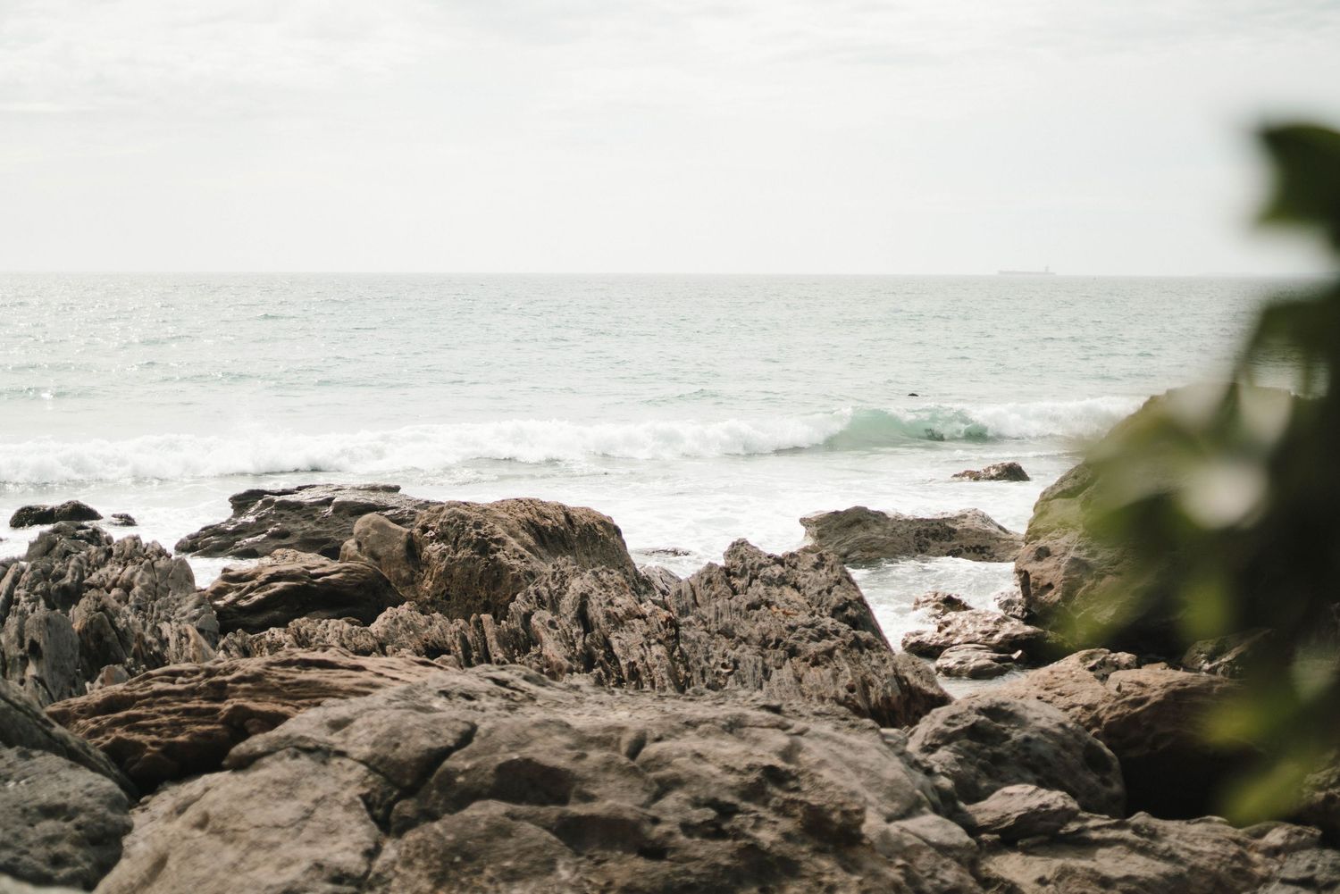 Rocky coastline with waves crashing against rugged cliffs and emerald green ocean waters stretching to the horizon.