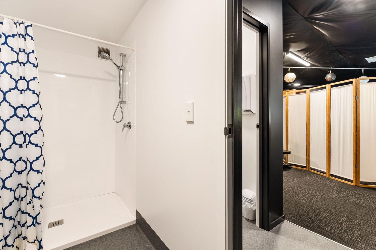 White corridor with blue geometric wall patterns, black carpet, and recessed lighting.