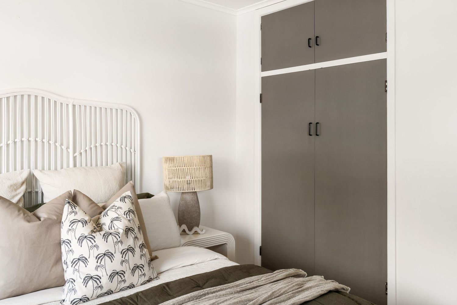 Minimalist white bedroom with built-in storage and neutral bedding.