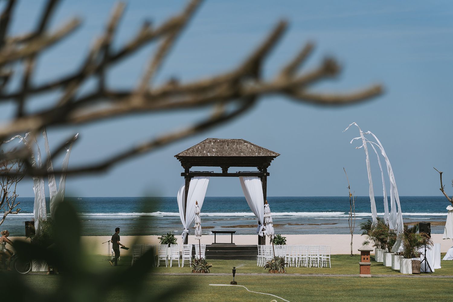 Beach wedding ceremony setup with white gazebo and chairs overlooking the ocean.