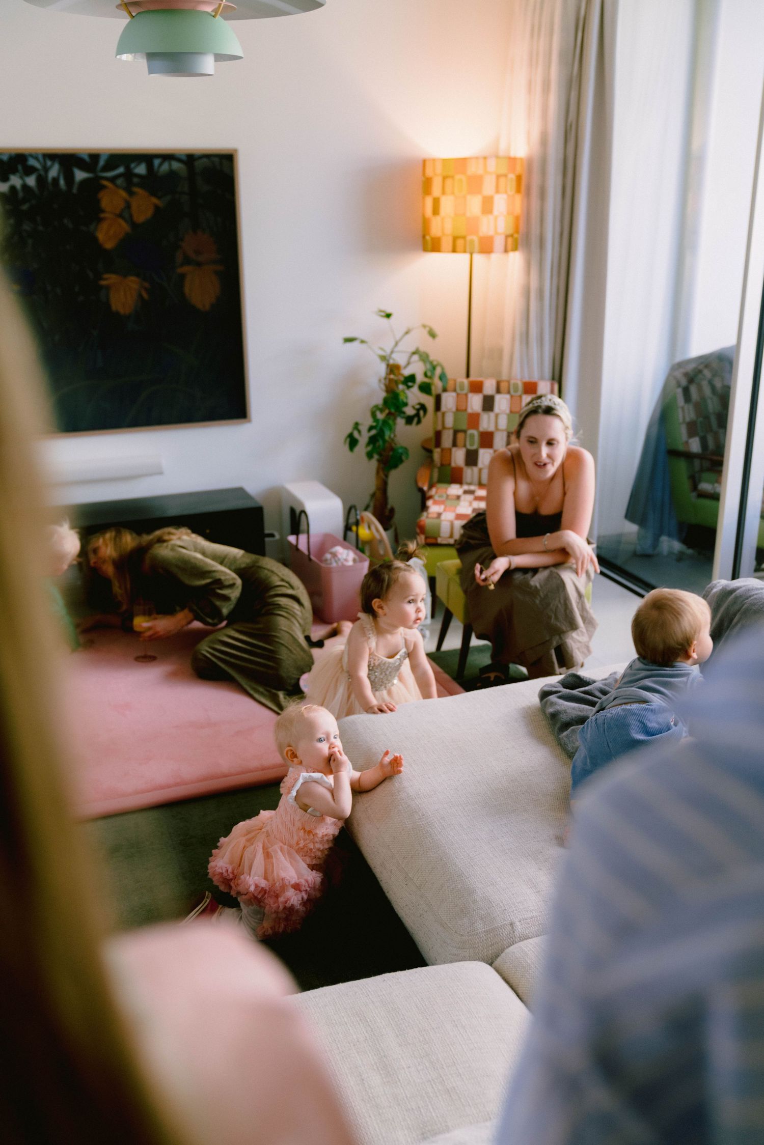A casual indoor gathering space with people relaxing on a couch near a window and decorative lamp.