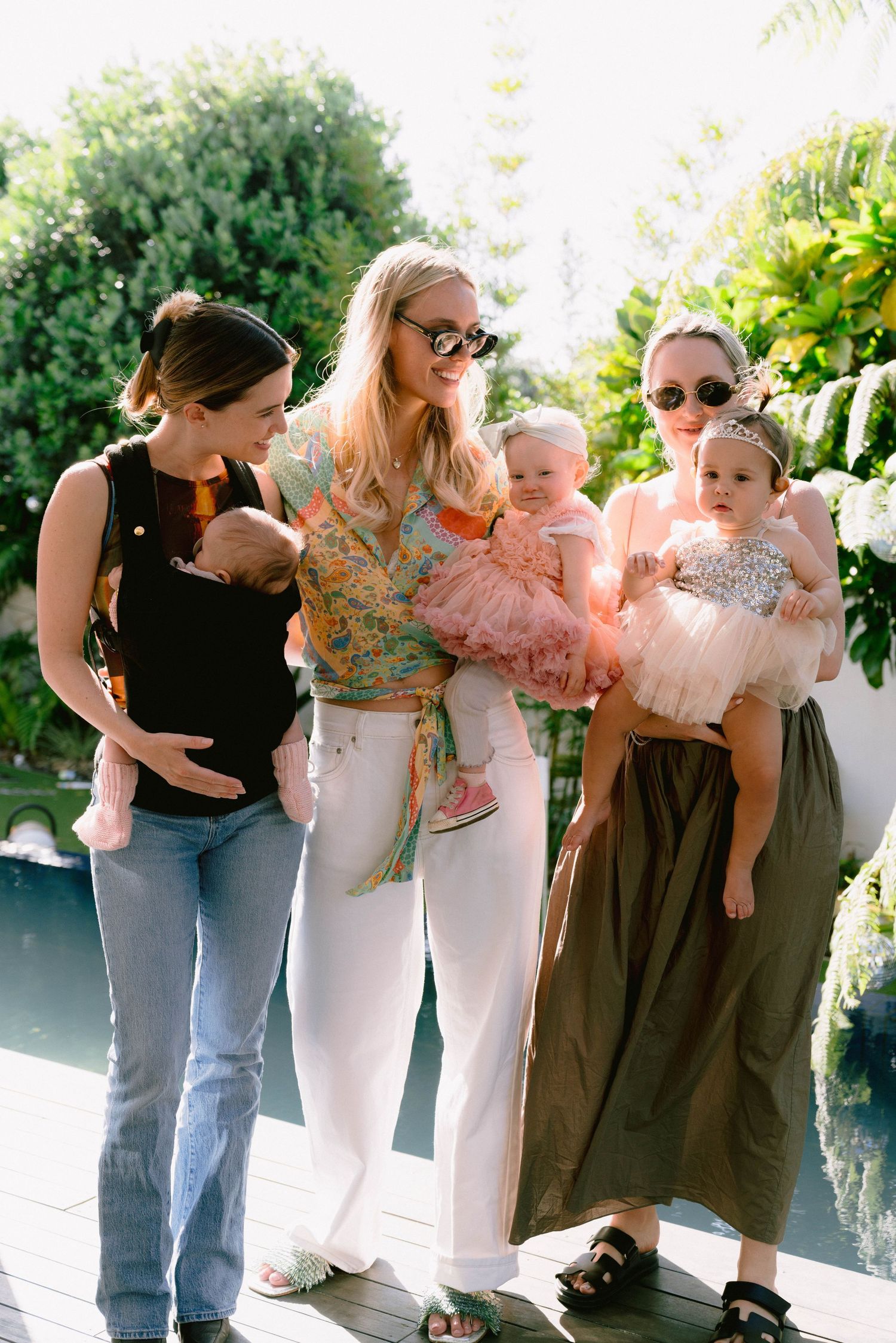 Group photo of party guests lined up wearing casual summer outfits near a pool.