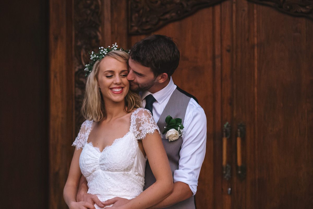 A joyful moment shared between newlyweds by a wooden doorway.