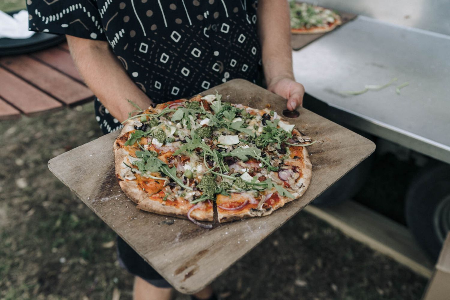 Fresh homemade pizza with arugula and cheese toppings served on brown parchment paper.