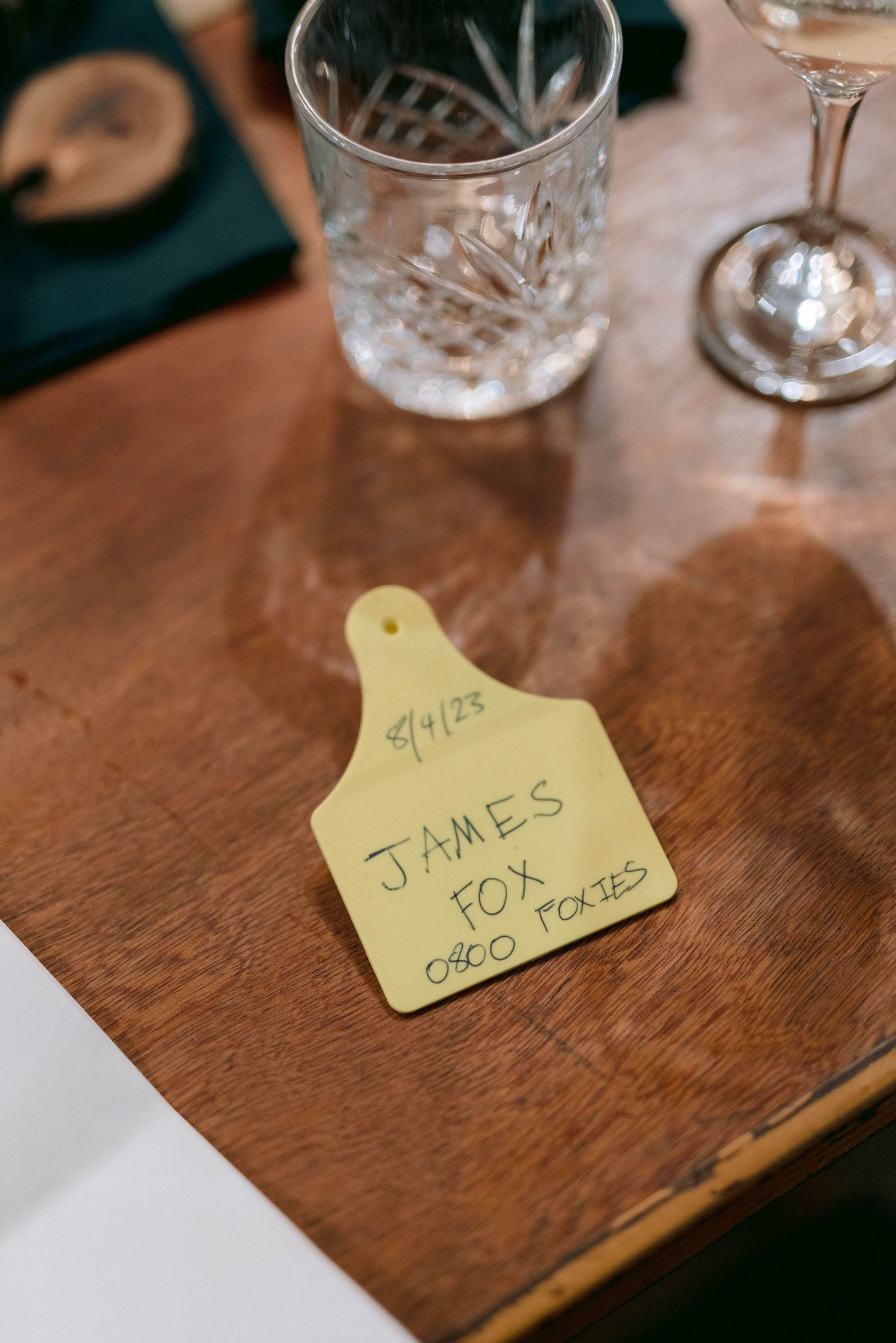 Yellow name place cards with handwritten text sit on a wooden dining table surface.