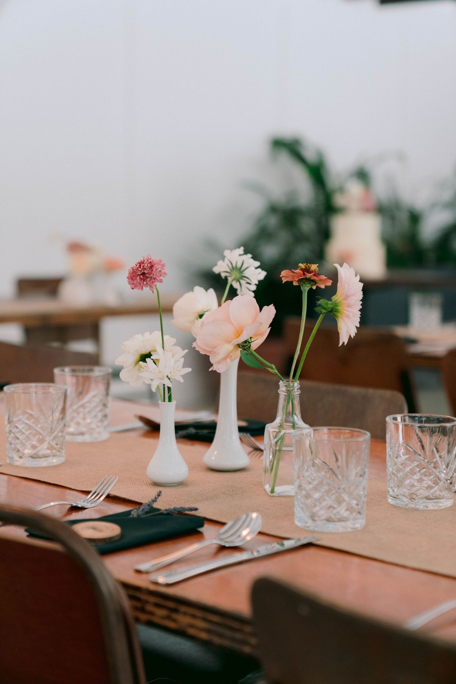 Elegant table settings with delicate flowers in crystal vases and peach-colored linens.