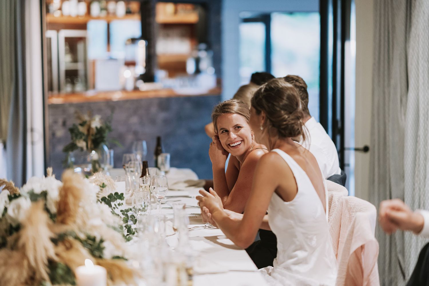 Wedding guests enjoying a lively reception celebration in an elegant indoor venue with natural lighting.