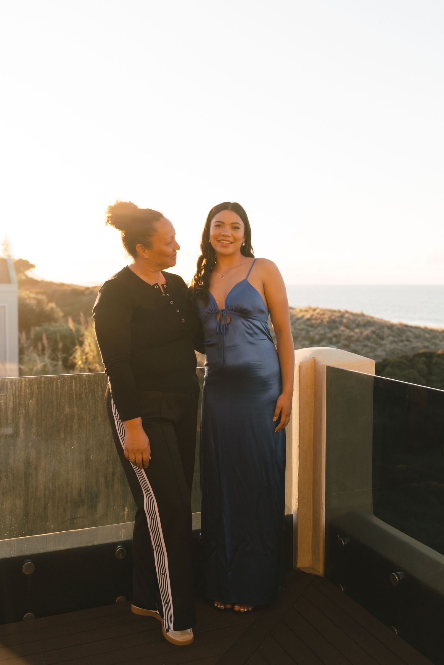 A couple shares a joyful moment together on an outdoor deck at sunset with mountains in the background.