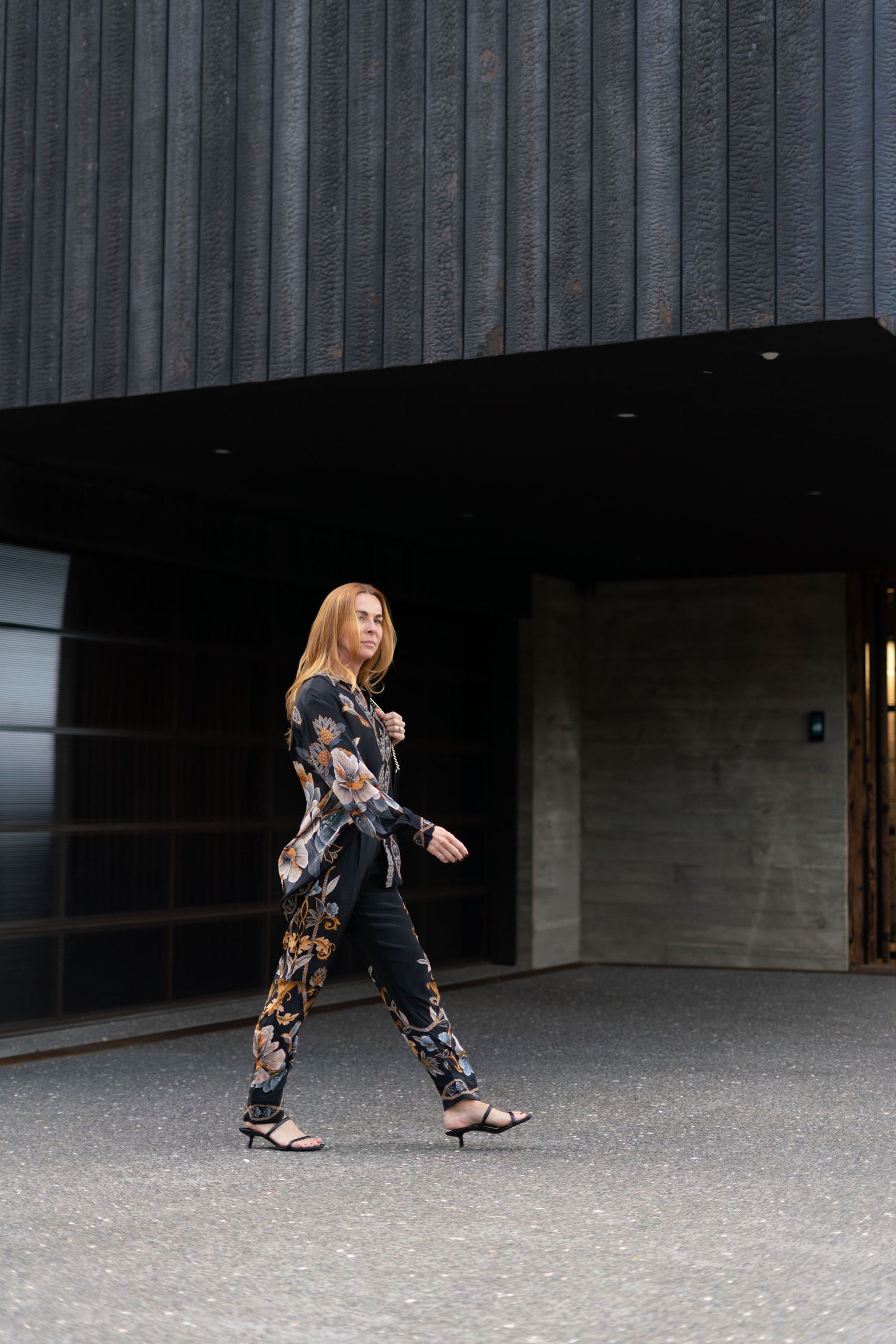 A series of motion shots shows a woman in flowered pants stretching forward into a lunge pose on a concrete surface.