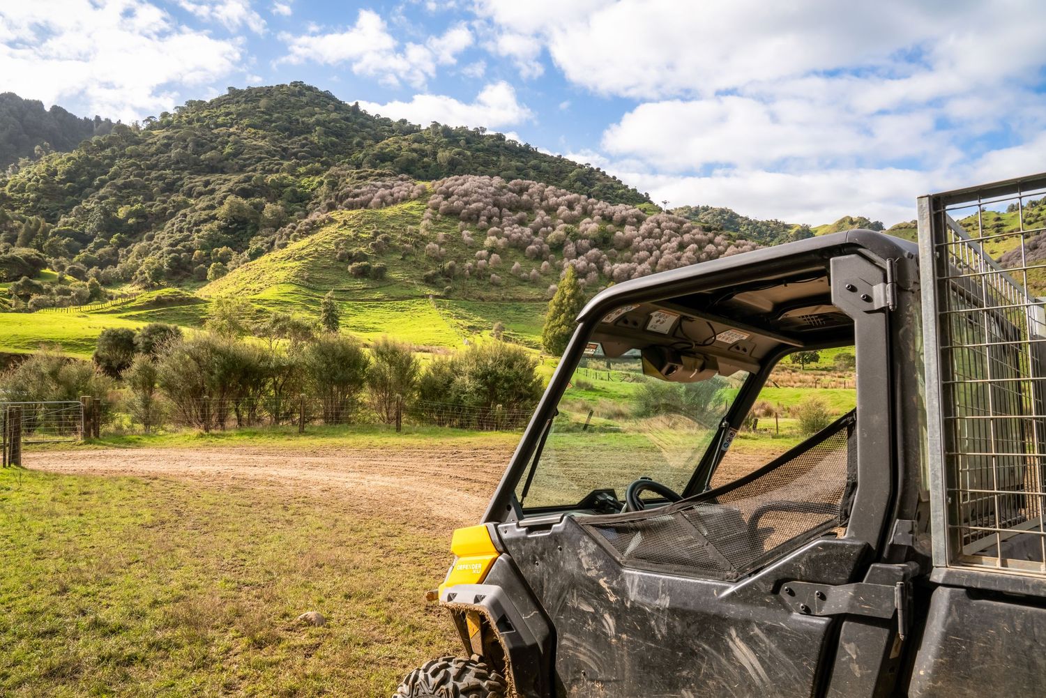 Off-road vehicle parked on hillside trail with expansive mountain valley views.