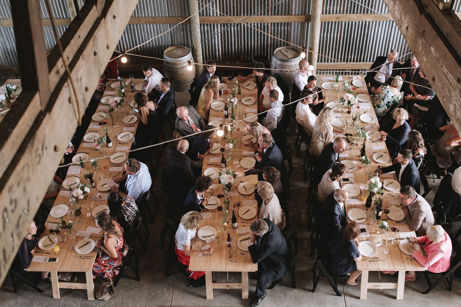 Overhead view of people seated at long wooden tables during a large communal dining event indoors.