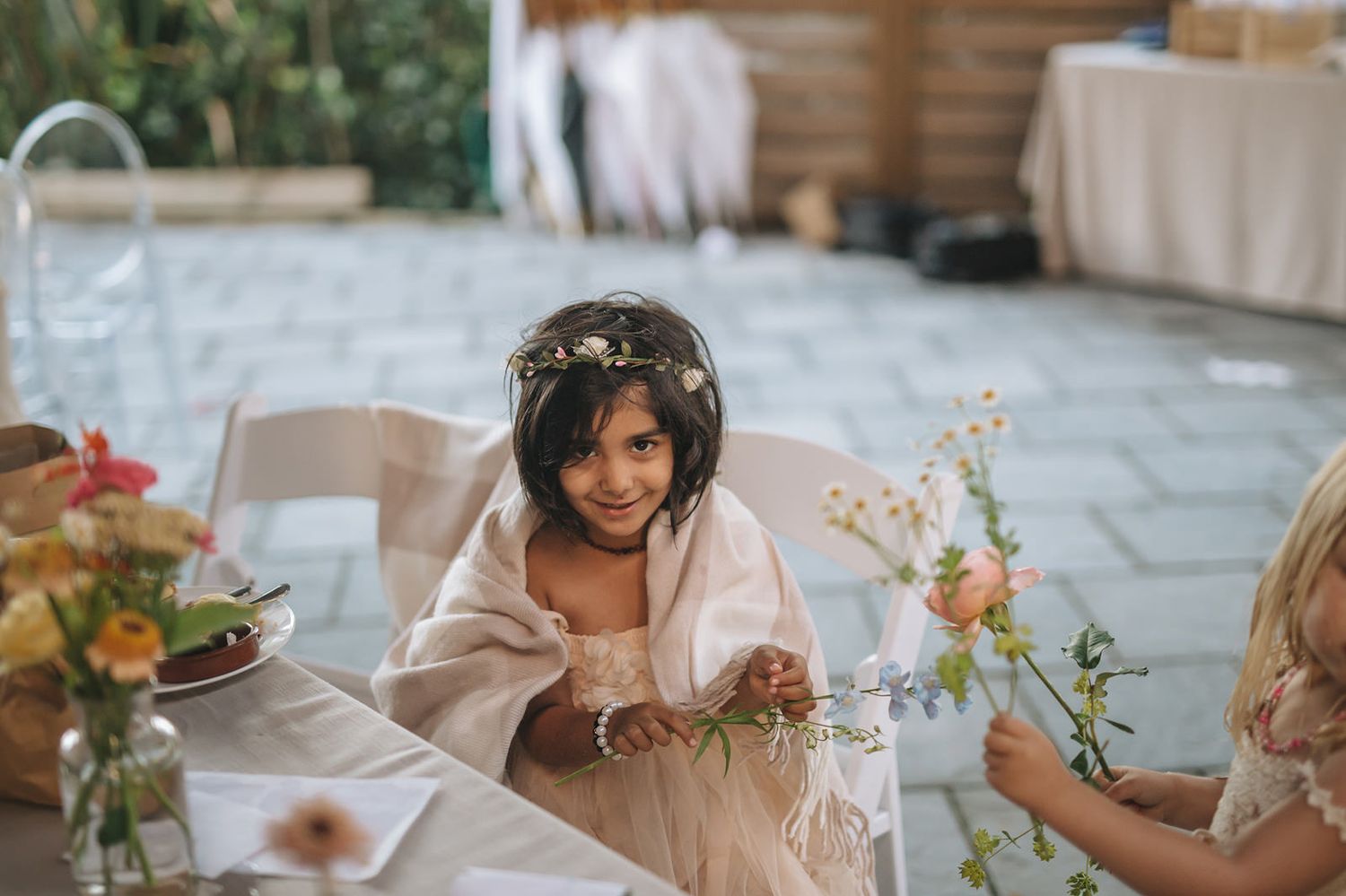 Wedding reception table decorated with floral arrangements and guests enjoying the atmosphere at a festive outdoor event.