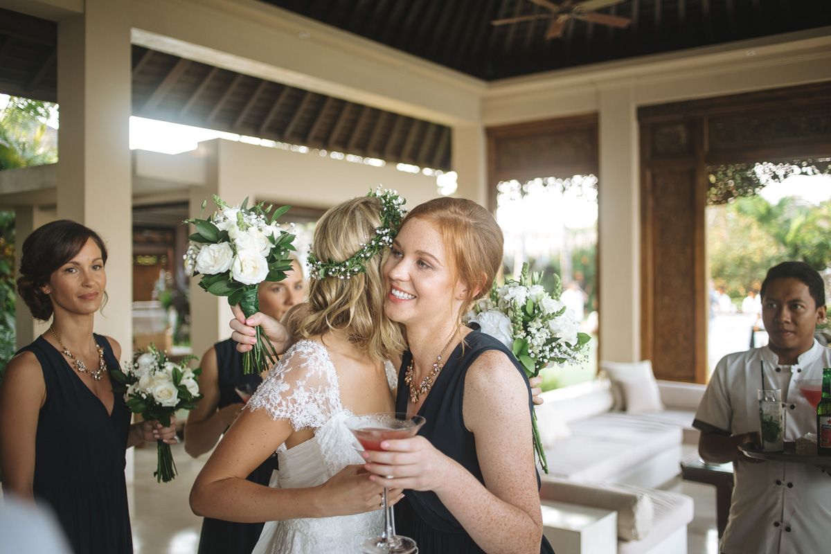 A touching moment at a wedding reception under a covered patio with white floral decorations.
