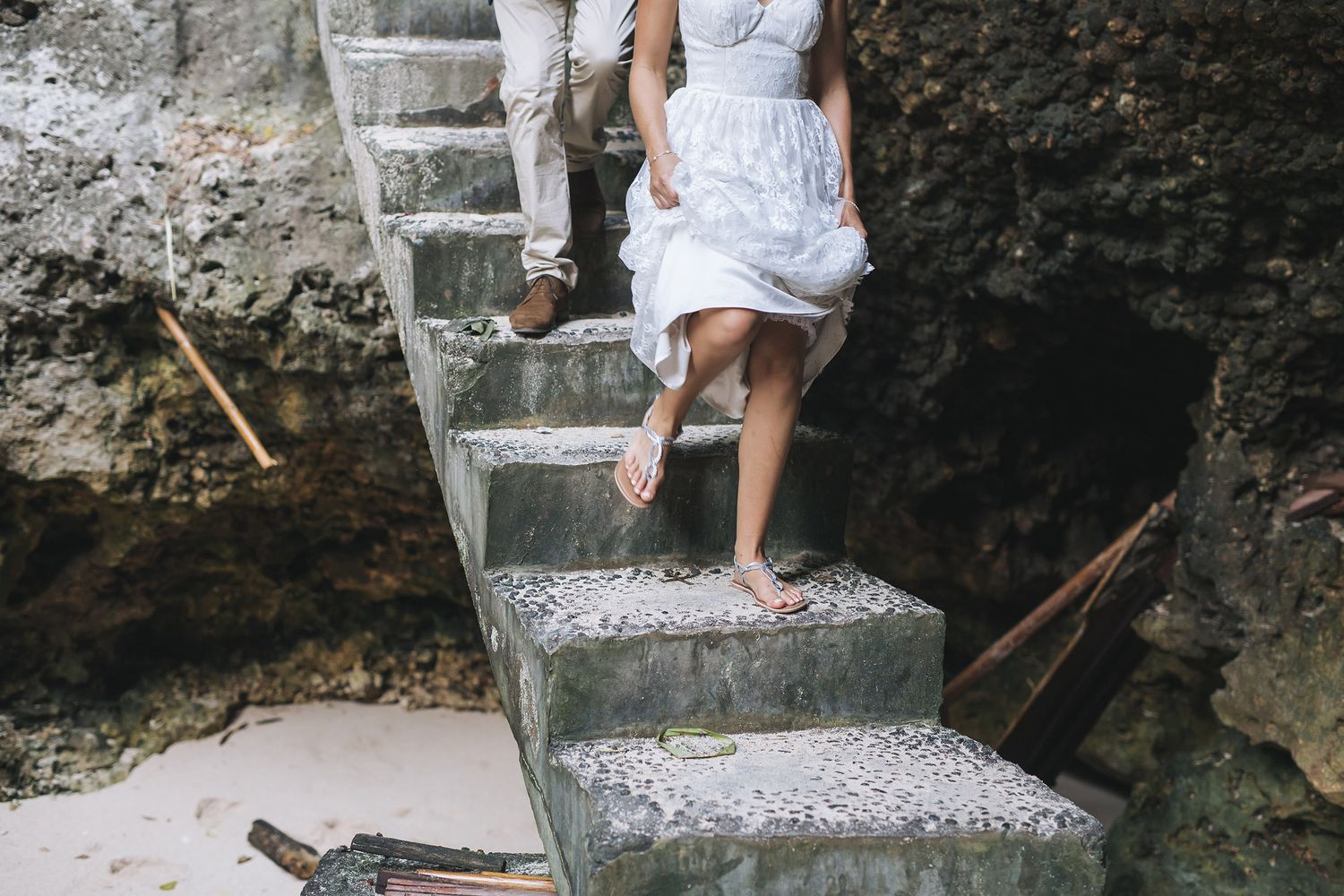 Wedding party members walking down stone steps while carrying decorative items for the ceremony.