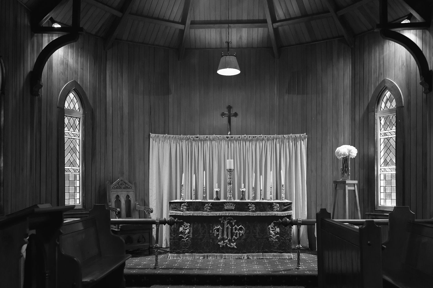 Interior view of a historic Gothic church sanctuary with wooden walls, vaulted ceiling, and traditional altar furnishings.