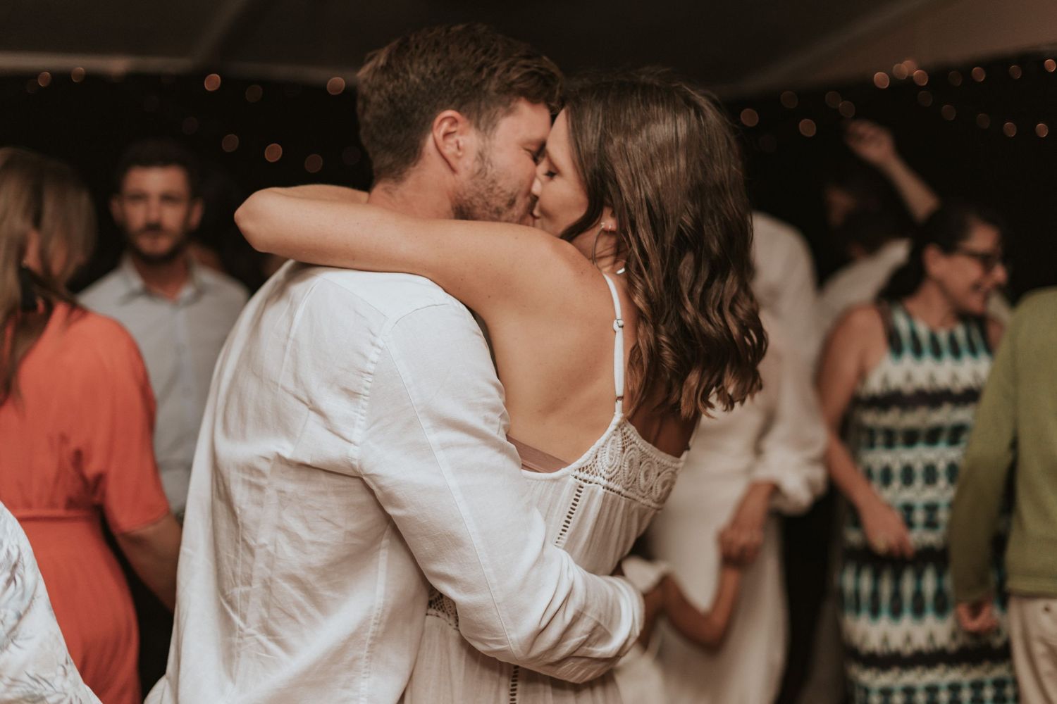 A couple shares a romantic dance among party guests during a wedding celebration.