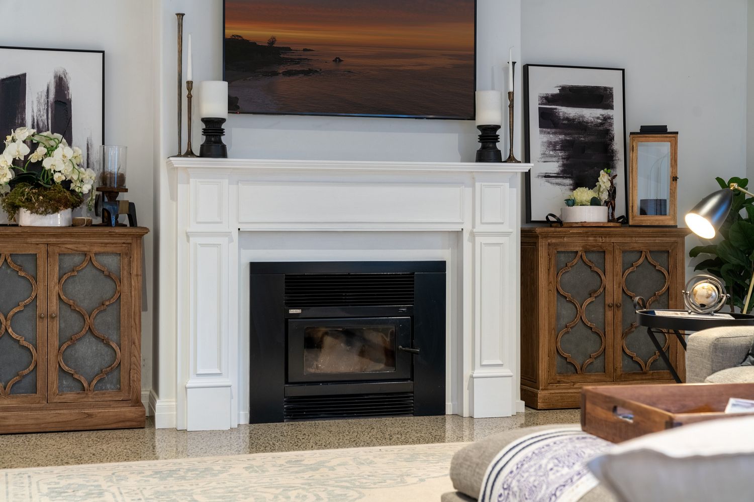 Modern living room features fireplace with white mantel and rustic wooden cabinets with decorative metalwork panels.