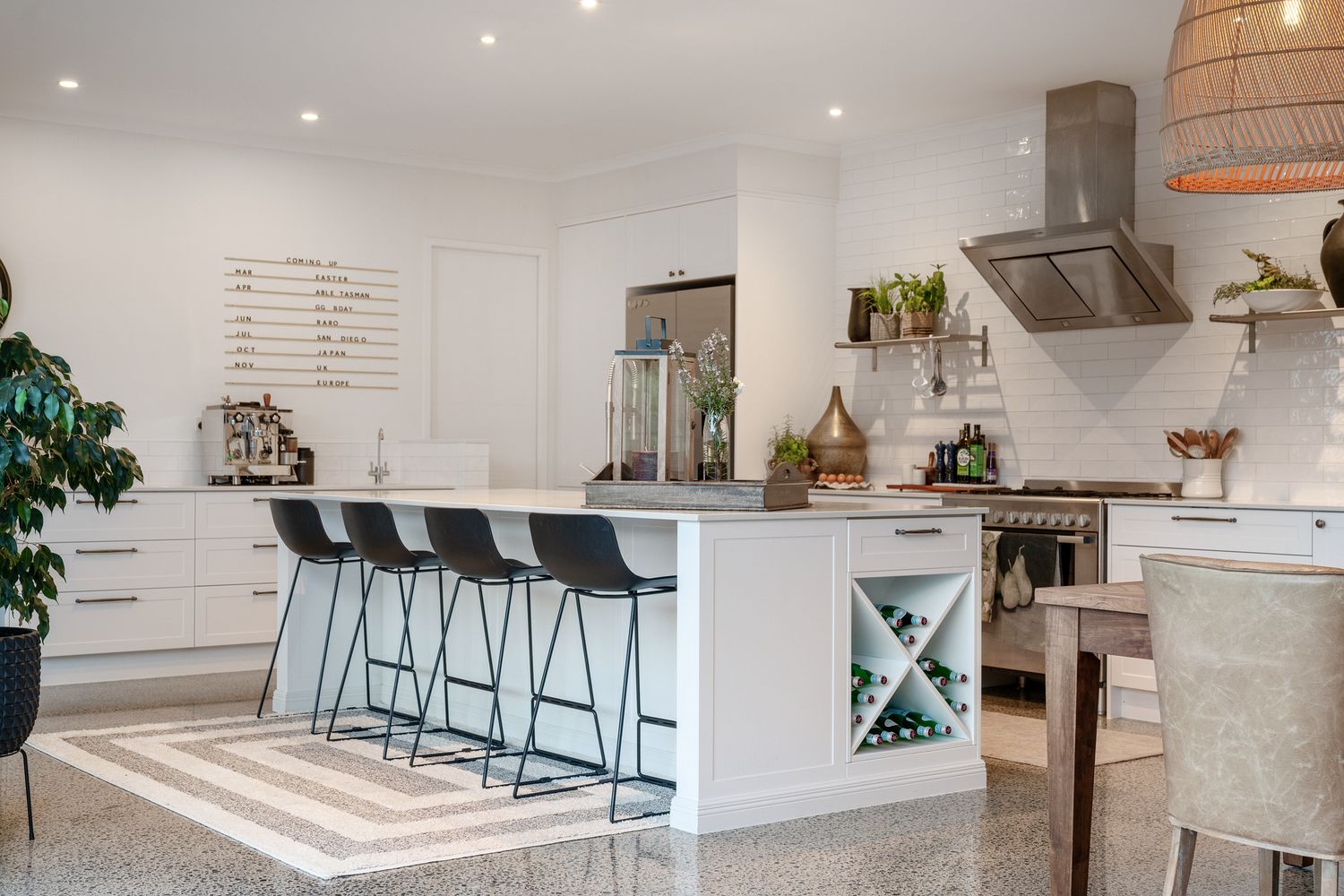 Open concept kitchen and living area with pendant lighting, white cabinets, and breakfast bar seating.