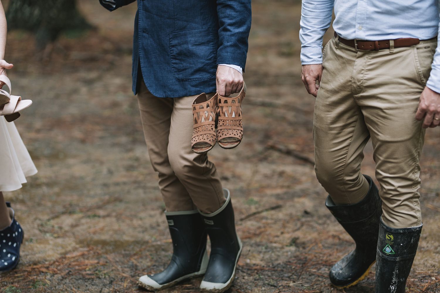 Low-angle view showing a line of people wearing khaki pants and black boots standing on natural terrain.