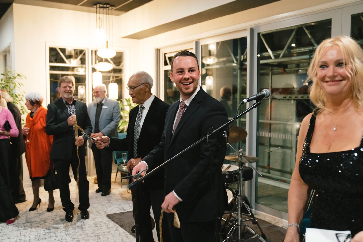 Well-dressed guests gather at an elegant indoor event space with modern lighting and decor.
