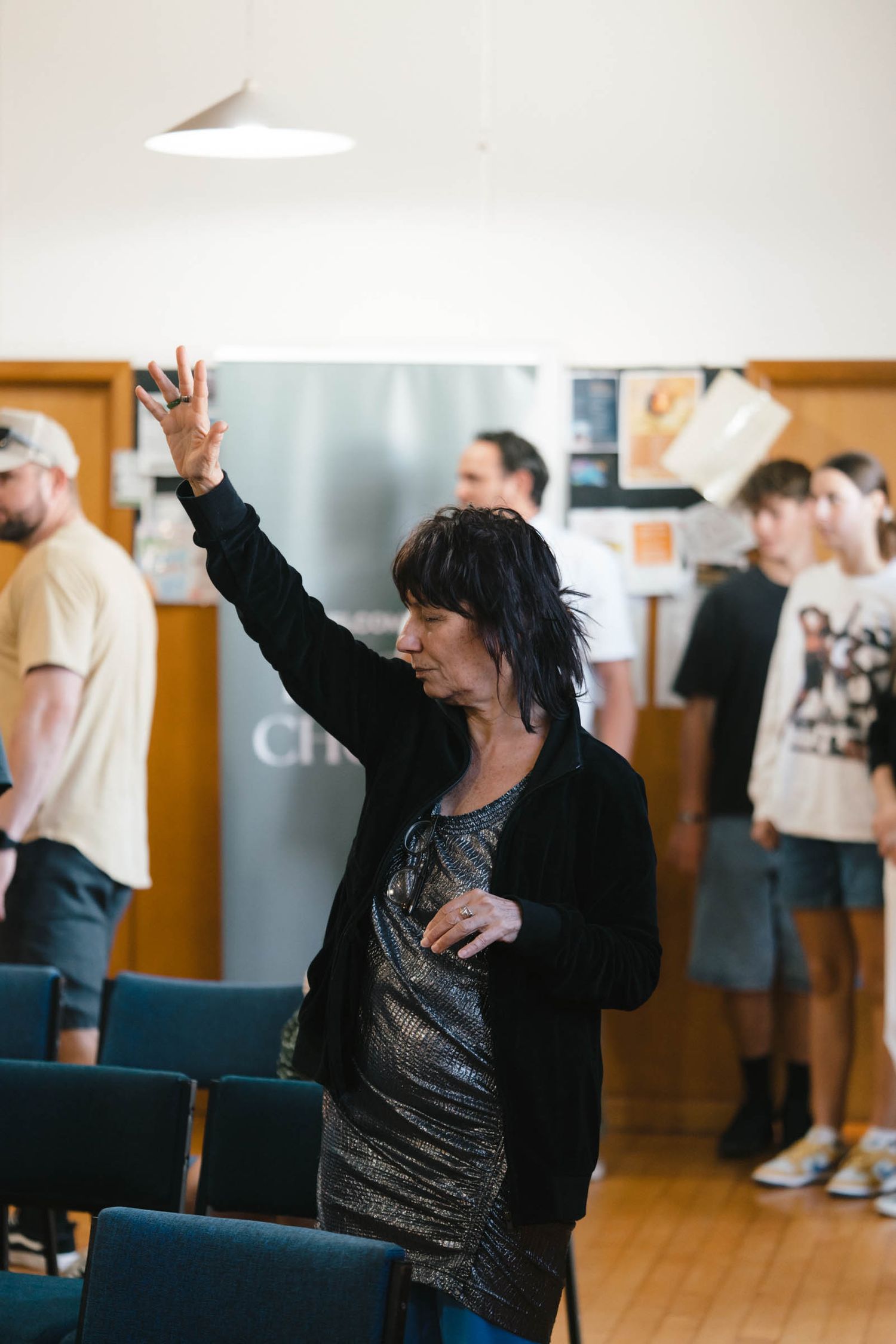 A person in black raising their hand during worship in a church setting.