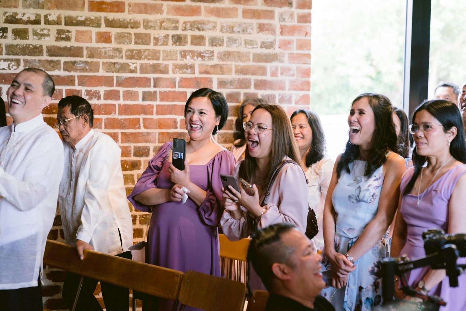 Wedding guests mingling and socializing in brick-walled reception space.