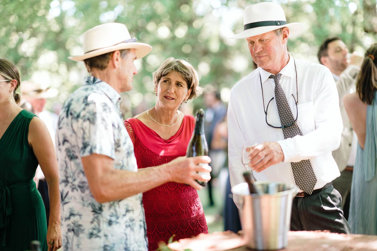 Guests mingling and having drinks under an outdoor tent at a garden party.