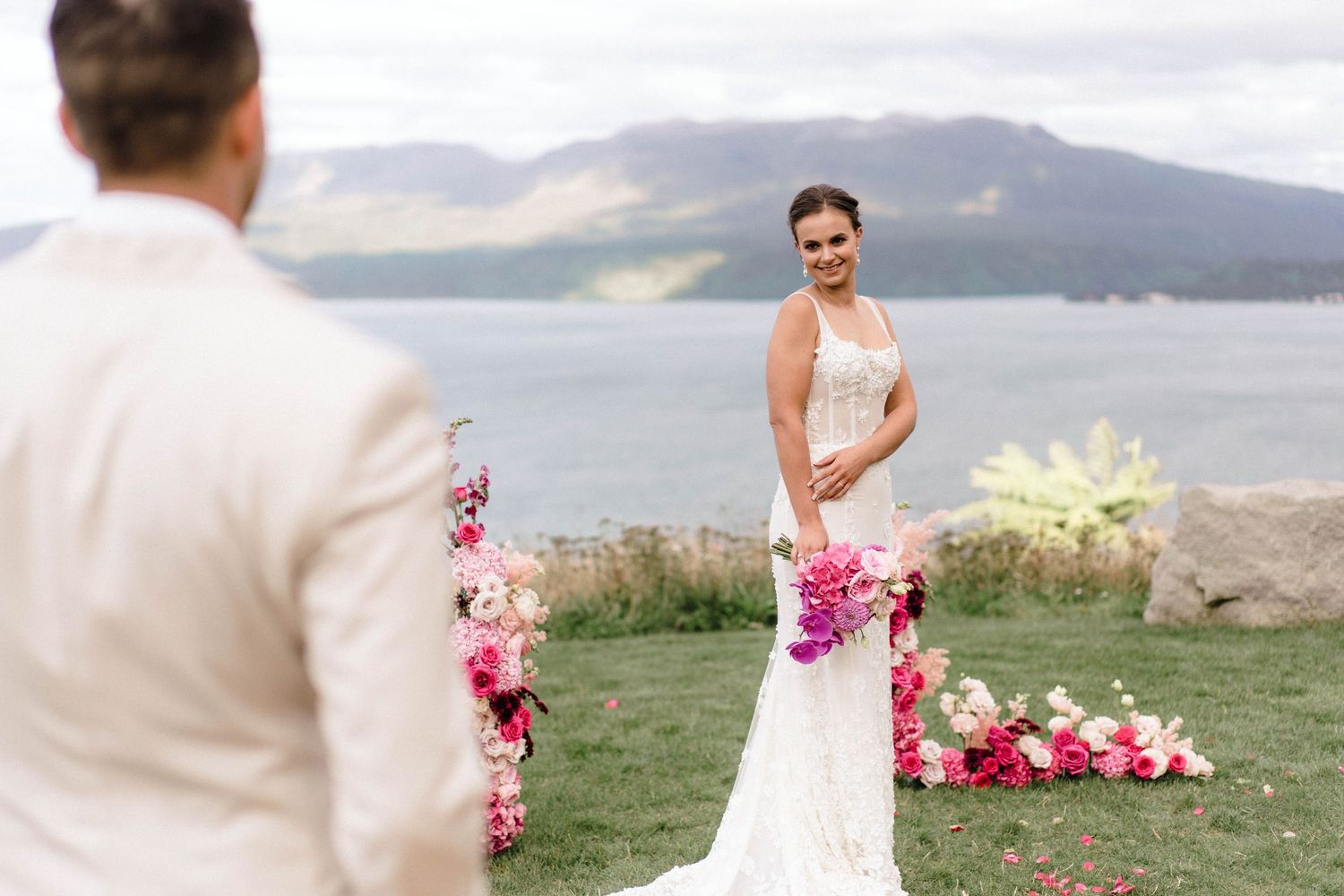 Scenic outdoor wedding setup with mountain views and pink floral decorations.