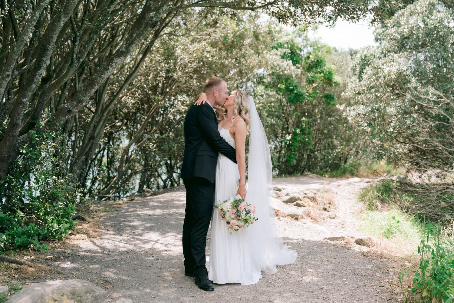 Couple walking together on a romantic wooded nature trail at a destination wedding venue.