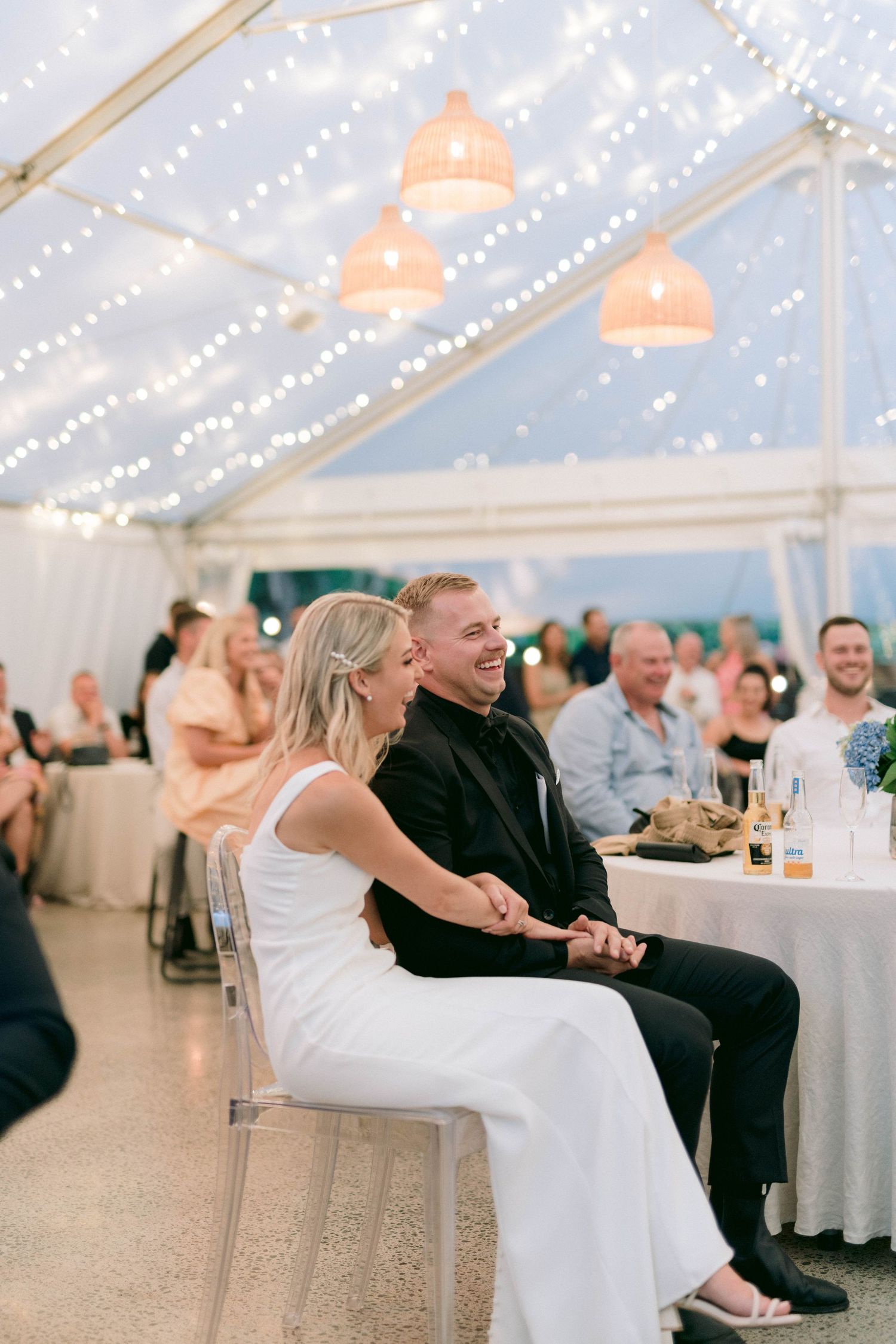 A couple shares a romantic dip dance moment under a tent decorated with string lights at an elegant reception.