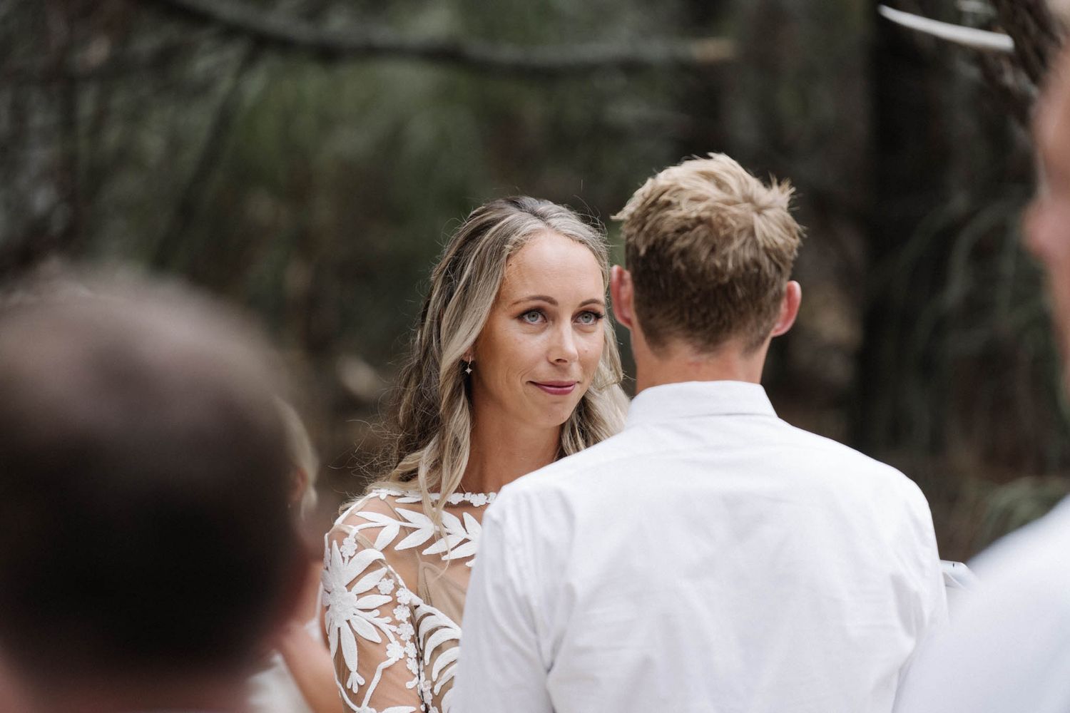 A couple exchanging vows during an intimate outdoor wedding ceremony in a wooded setting.