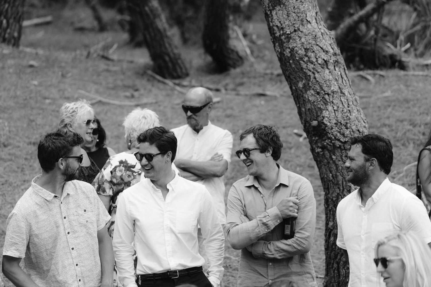 A black and white photo mosaic showing multiple groups of people gathered outdoors in casual conversation.