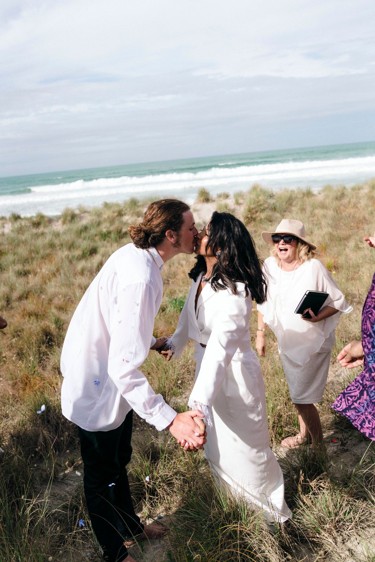 A joyful celebration unfolds among friends on a scenic beach hillside.