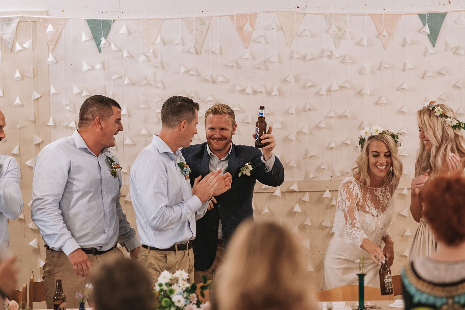 A festive wedding reception with bunting and dancing guests celebrating in a rustic white brick venue.