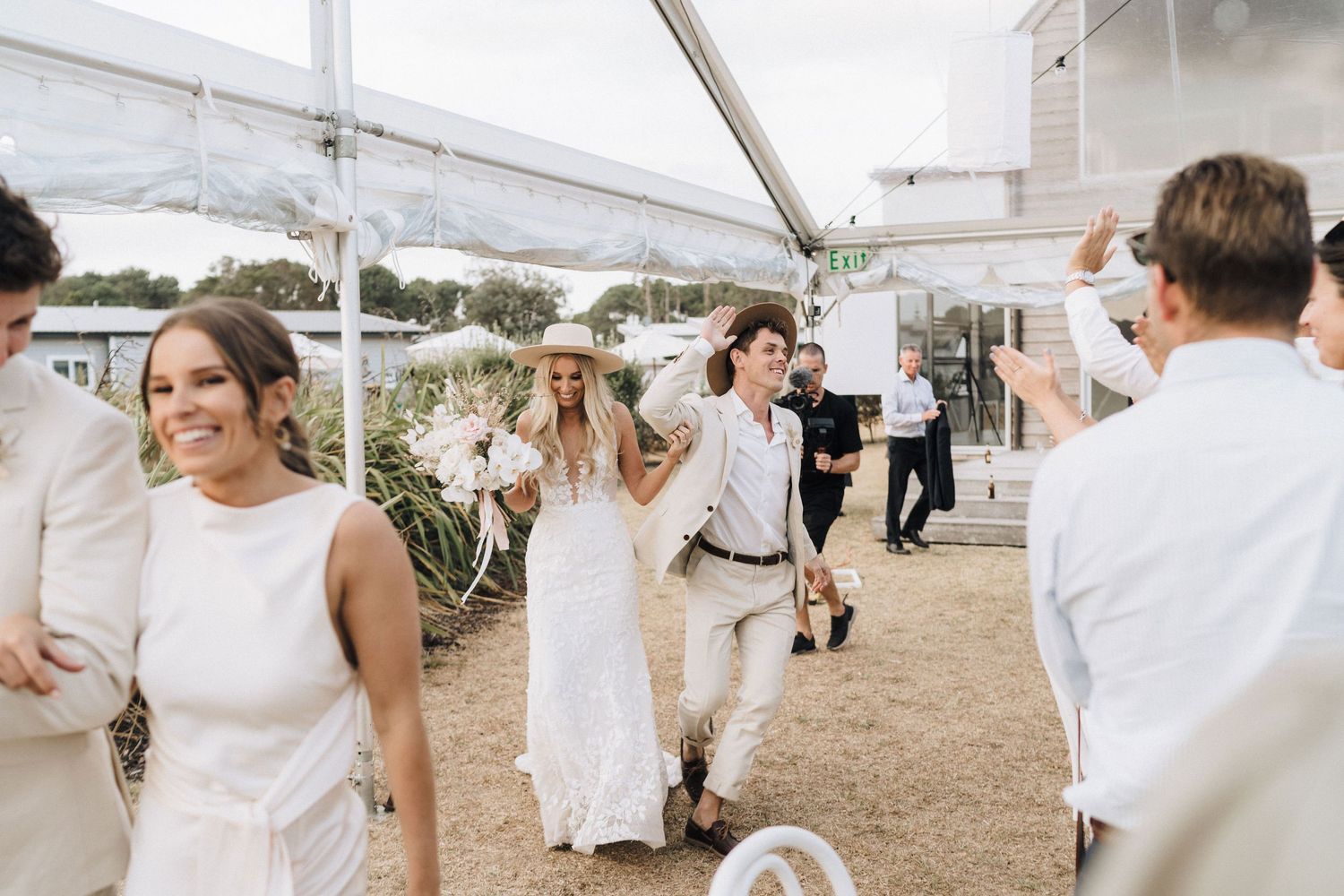 White-themed outdoor wedding ceremony setup with chairs and floral arrangements on a beach.