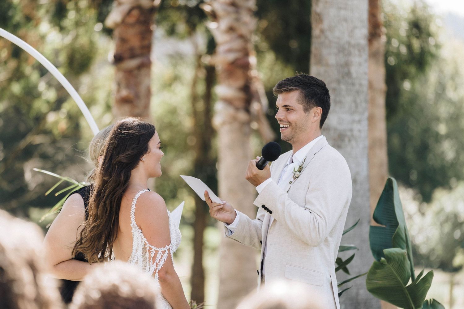 Intimate outdoor wedding ceremony taking place among tropical palm trees.