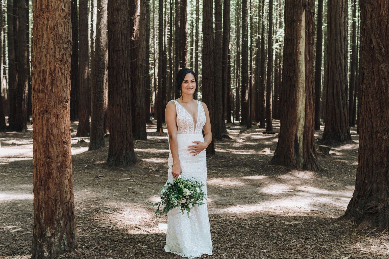 Scenic forest wedding photography displaying pine trees and flowing white dress.