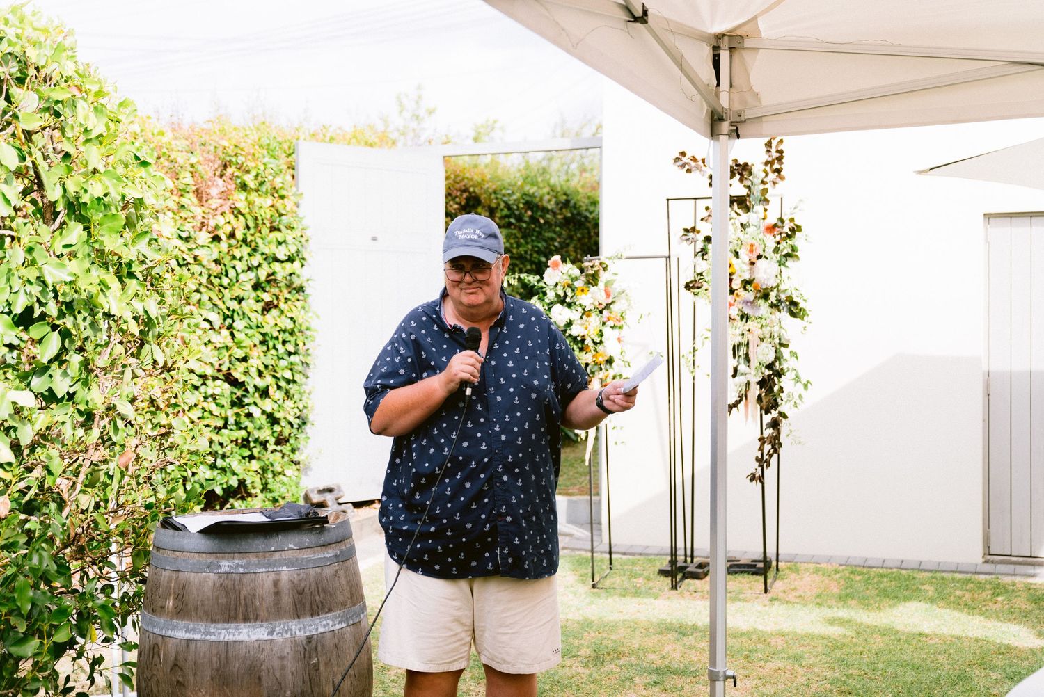 Garden party setting with rustic wine barrels and white tent canopy.