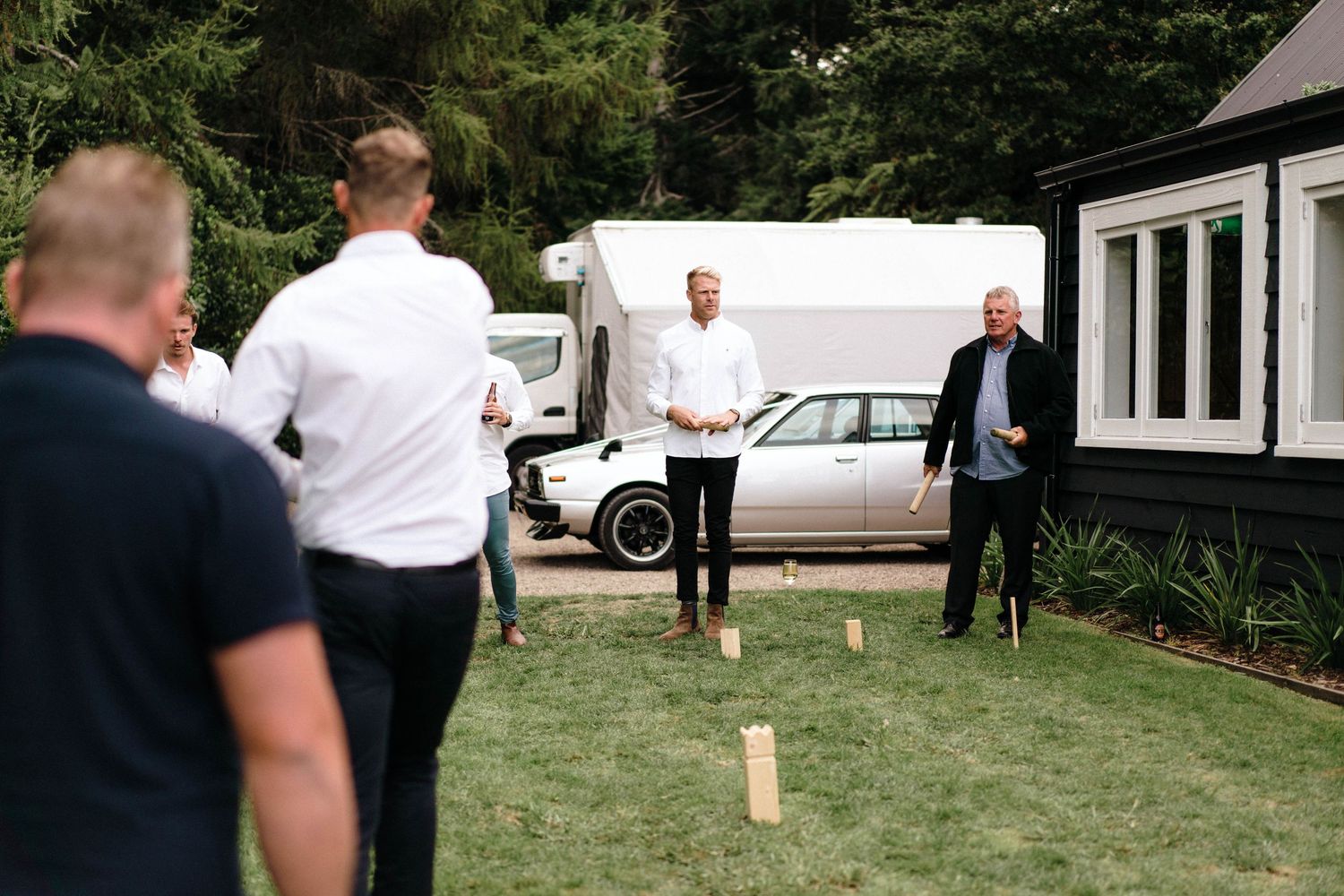 White tents and outdoor wedding setup on grassy lawn with trees.