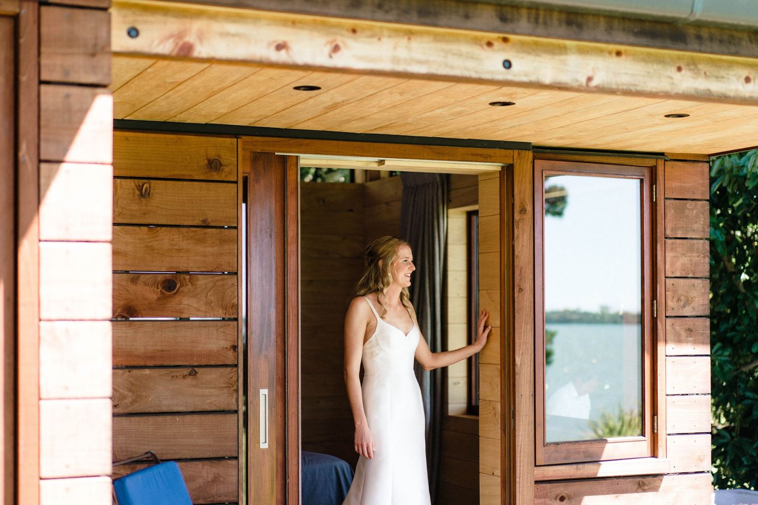 Rustic wooden cabin interior with windows and doorways overlooking a scenic waterfront view.