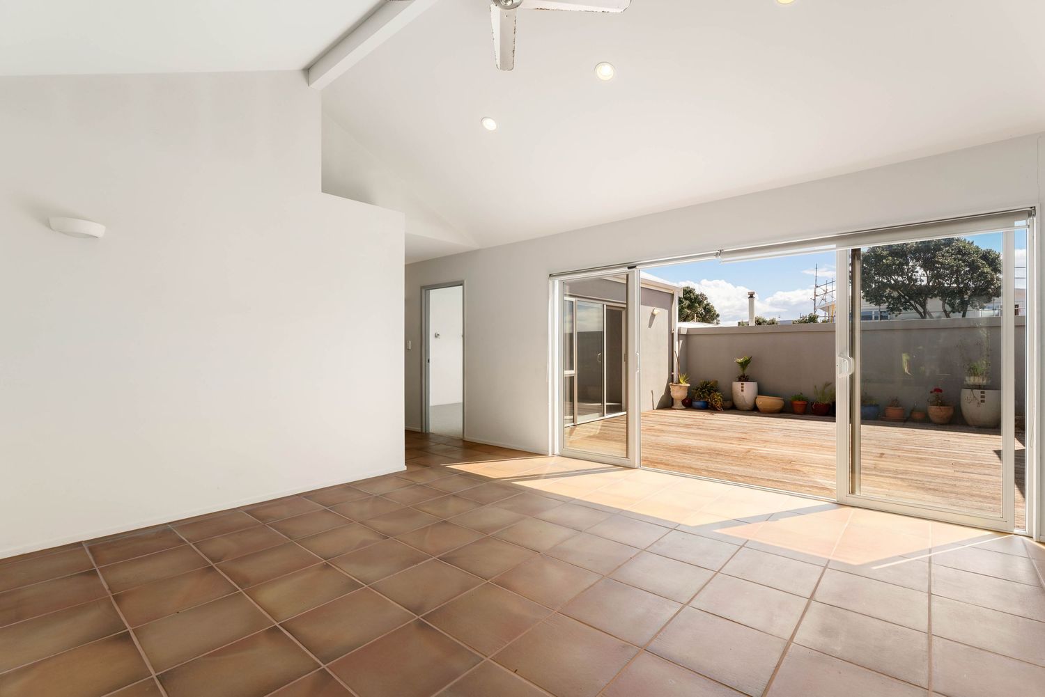 Spacious room with terracotta flooring and large glass sliding doors leading to outdoor space.