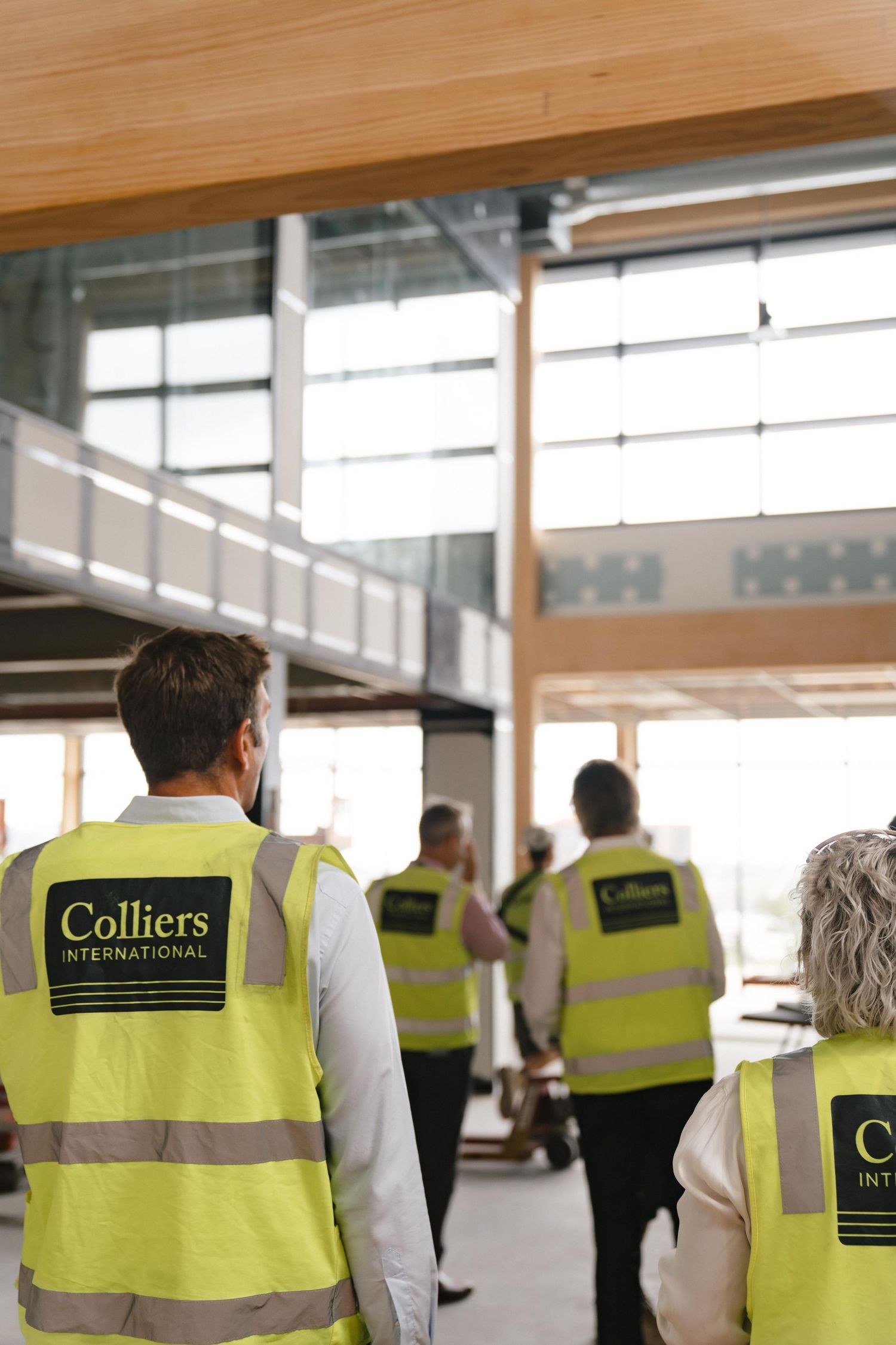 Construction site workers in Colliers high-visibility vests inspecting a commercial building interior.