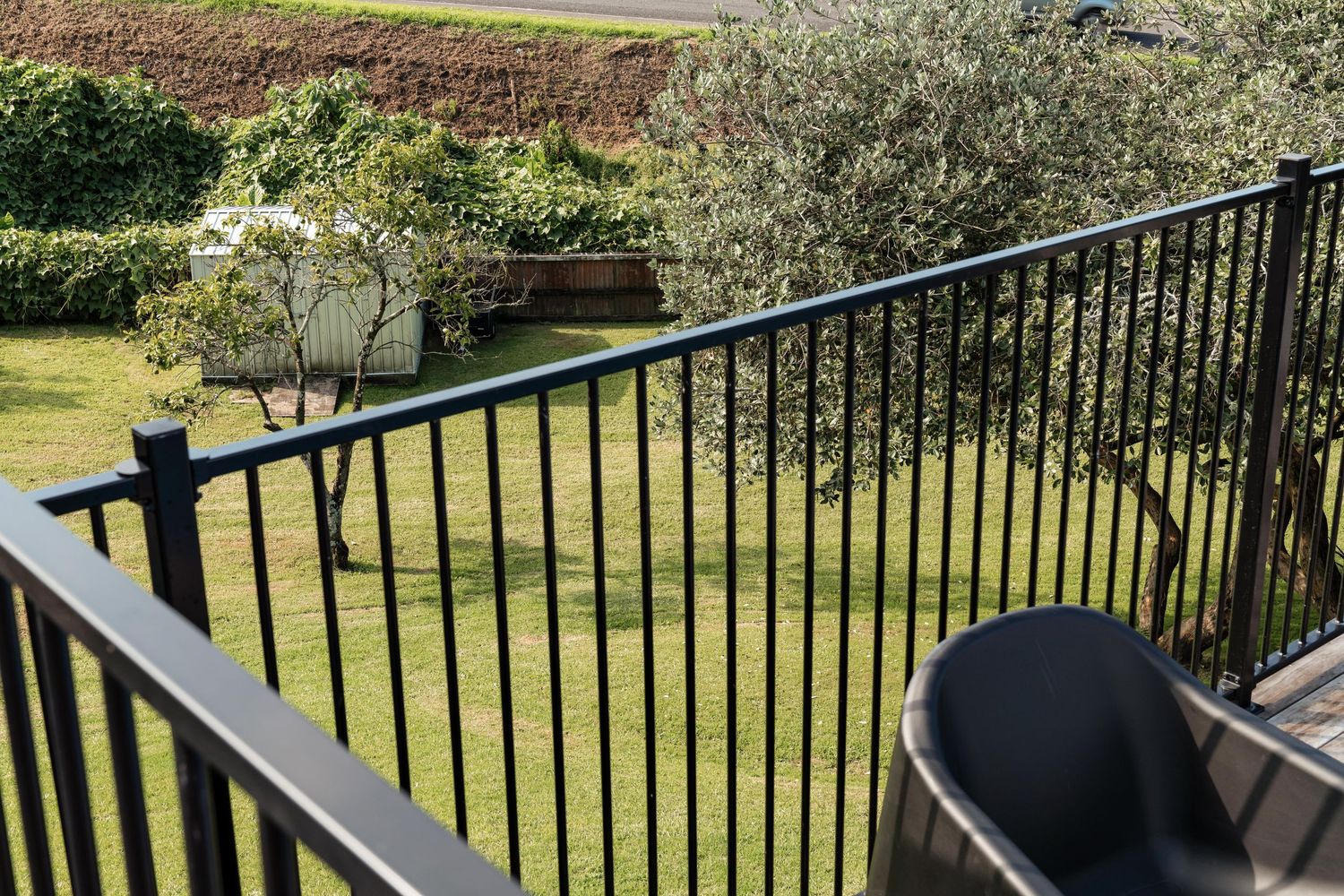 Modern black metal balcony railing overlooking a well-maintained green lawn.
