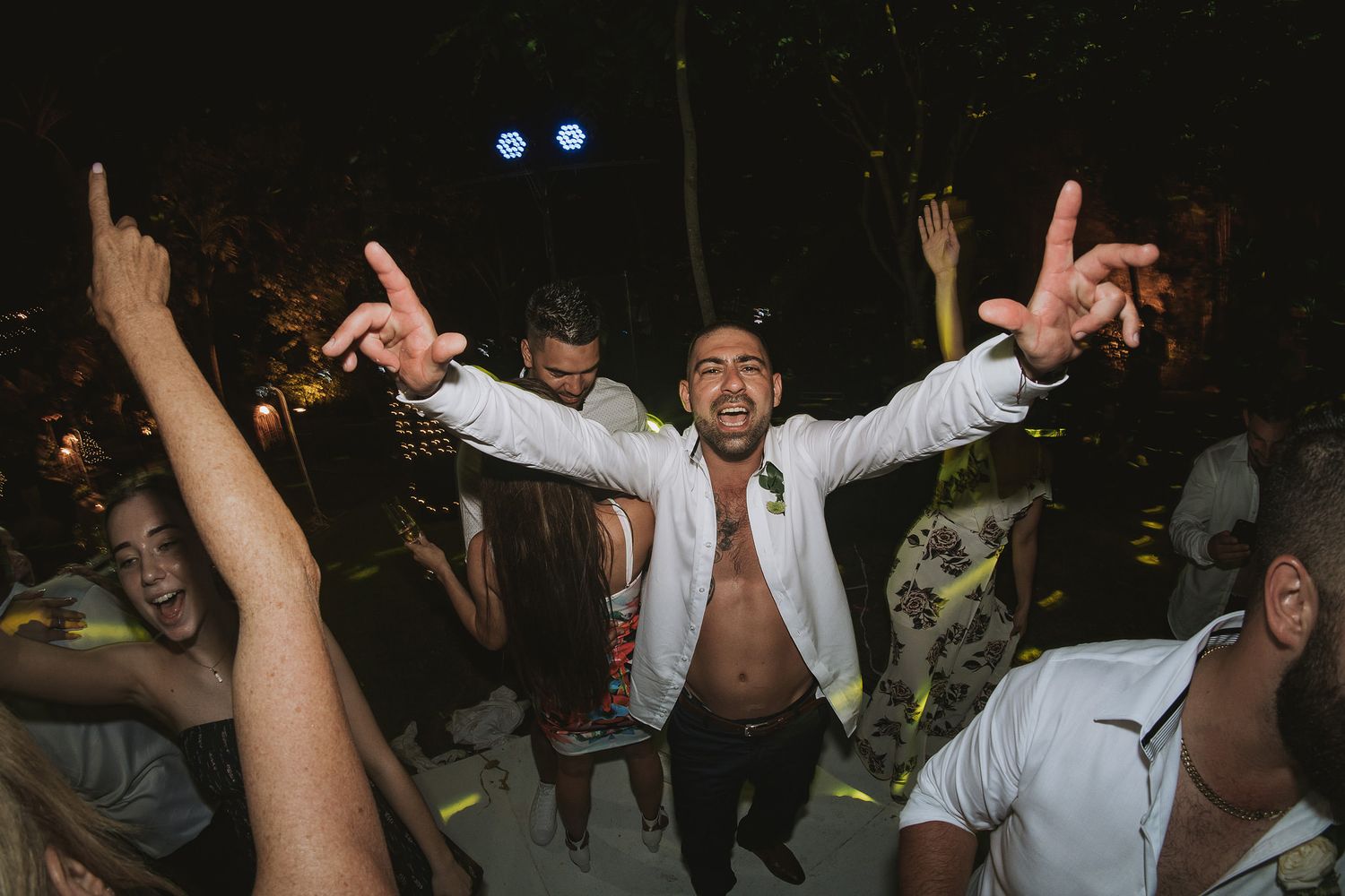 An energetic party scene with guests dancing and celebrating under night lights.