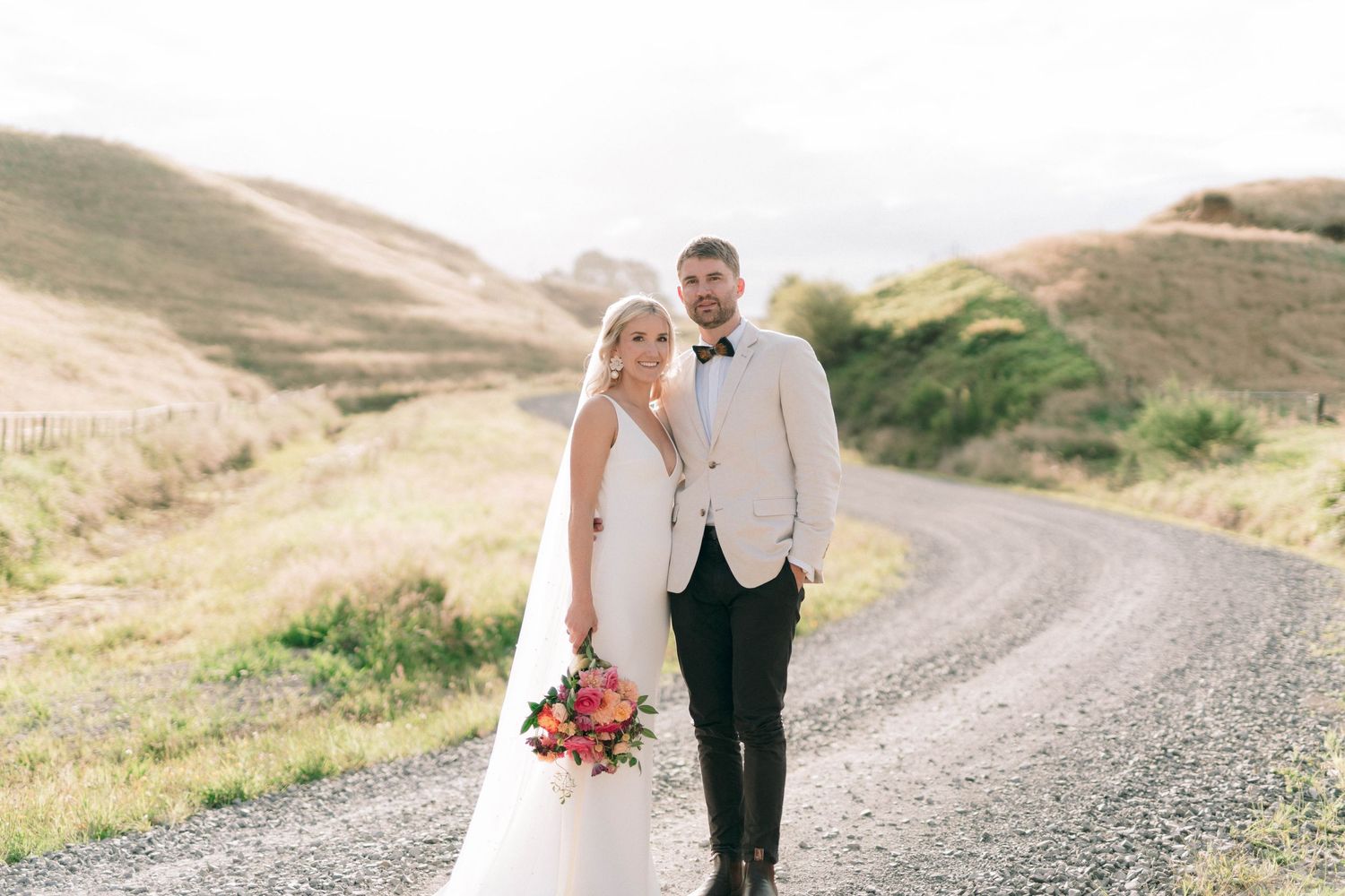Couple walks together on country road surrounded by rolling green hills.