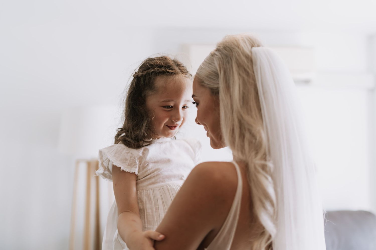 A tender intimate moment shared between two figures wearing white against a light background.