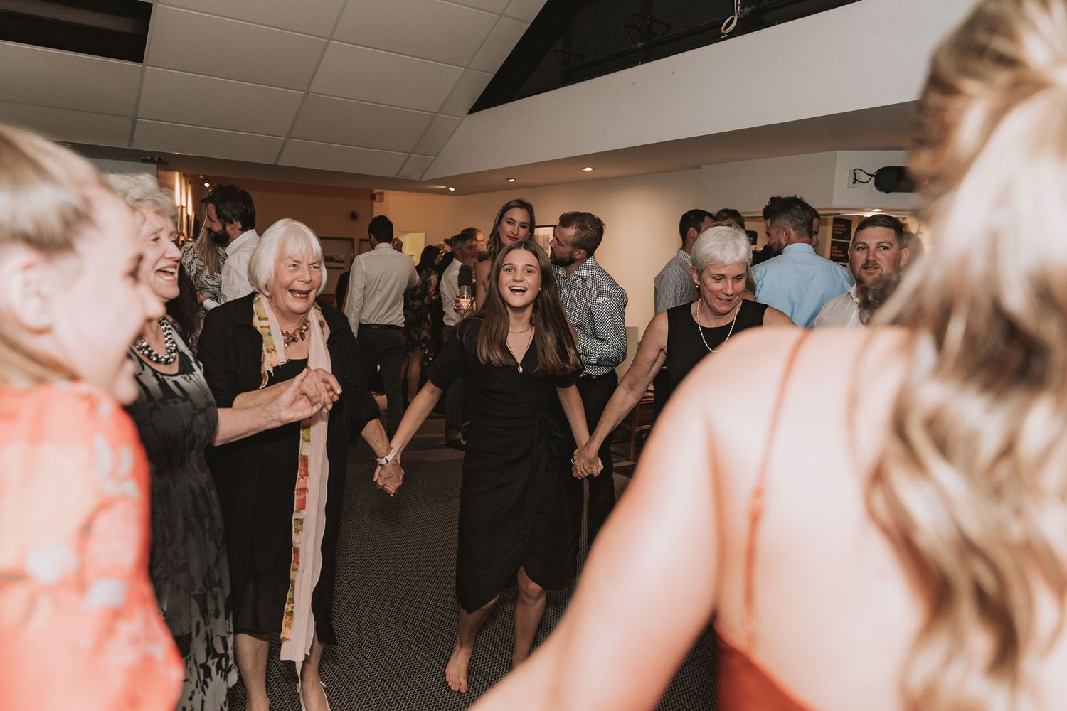 A blurry action shot shows people dancing together at a lively indoor party or celebration event.